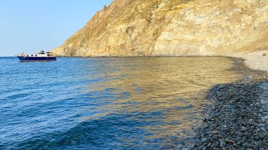 Gökceada Yıldız Körfezi 'nin yanındaki Blue Bay (Mavi Koy) deniz manzarası ve körfeze demirlemiş bir tekne. Imbros Adası, Canakkale, Türkiye