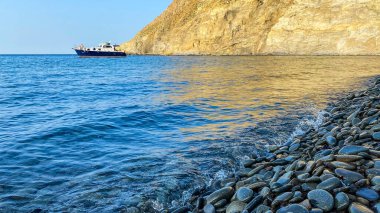 Gökceada Yıldız Körfezi 'nin yanındaki Blue Bay (Mavi Koy) deniz manzarası ve körfeze demirlemiş bir tekne. Imbros Adası, Canakkale, Türkiye