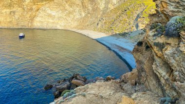 Gökceada Yıldız Körfezi 'nin yanındaki Blue Bay (Mavi Koy) deniz manzarası ve körfeze demirlemiş bir tekne. Imbros Adası, Canakkale, Türkiye