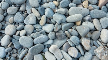 Sahildeki çakıl taşlarının yakın görüntüsü. Soyut doğa çakıl taşı arka planı. Kumsalda küçük deniz taşları, denizde tatil. Üst Manzara. Zen dengesi, minimalizm, uyum ve barış