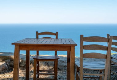 Gökçeada (Imbros) kıyı şeridi ve ahşap sandalyeli ve masalı şirin bir köy çay bahçesi manzarası. Tepeky köyü, Naralt-Pinarbasi bölgesi, Ege Türkiye