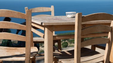 Gökçeada (Imbros) kıyı şeridi ve ahşap sandalyeli ve masalı şirin bir köy çay bahçesi manzarası. Tepeky köyü, Naralt-Pinarbasi bölgesi, Ege Türkiye