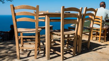 Gökçeada (Imbros) kıyı şeridi ve ahşap sandalyeli ve masalı şirin bir köy çay bahçesi manzarası. Tepeky köyü, Naralt-Pinarbasi bölgesi, Ege Türkiye