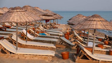 Gün batımında Gkeada Aydincik (Kefalos) plajında boş güneş pansiyonları ve şemsiyeler