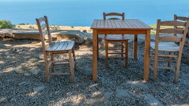 Gökçeada (Imbros) kıyı şeridi ve ahşap sandalyeli ve masalı şirin bir köy çay bahçesi manzarası. Tepeky köyü, Naralt-Pinarbasi bölgesi, Ege Türkiye