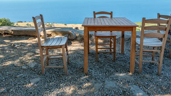 Gökçeada (Imbros) kıyı şeridi ve ahşap sandalyeli ve masalı şirin bir köy çay bahçesi manzarası. Tepeky köyü, Naralt-Pinarbasi bölgesi, Ege Türkiye