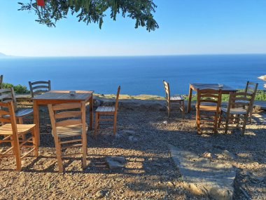 Gökçeada (Imbros) kıyı şeridi ve ahşap sandalyeli ve masalı şirin bir köy çay bahçesi manzarası. Tepeky köyü, Naralt-Pinarbasi bölgesi, Ege Türkiye