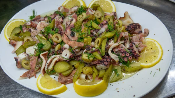 Haşlanmış ahtapot salatası saf zeytin yağı, limon dilimleri, dereotu, yeşil zeytin ve salatalık turşusuyla servis edilir. Taze ve sağlıklı deniz ürünleri salatası. Akdeniz gurme aperatifi.