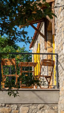 Bir Akdeniz-Ege kır evinin küçük balkonunda tahta masa ve sandalyeler.