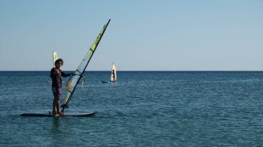Gökçeada, Canakkale Türkiye 29 Temmuz 2023; Ege Denizi 'nin tadını çıkaran rüzgar sörfçüleri ve açık gökyüzüne karşı Gökçeada Kefalos Körfezi' nde esen rüzgar. Imbros Adası. 