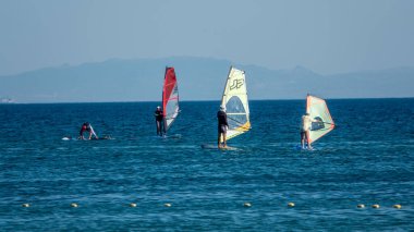 Gökçeada, Canakkale Türkiye 29 Temmuz 2023; Ege Denizi 'nin tadını çıkaran rüzgar sörfçüleri ve açık gökyüzüne karşı Gökçeada Kefalos Körfezi' nde esen rüzgar. Imbros Adası. 