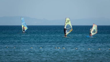 Gökçeada, Canakkale Türkiye 29 Temmuz 2023; Ege Denizi 'nin tadını çıkaran rüzgar sörfçüleri ve açık gökyüzüne karşı Gökçeada Kefalos Körfezi' nde esen rüzgar. Imbros Adası. 