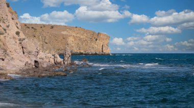 Gökyüzündeki bulut kümeleri ıssız bir sahilde muhteşem kayalıklar ve deniz dalgalarıyla