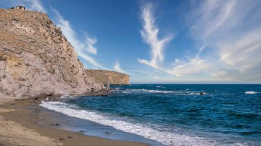 Gökyüzündeki bulut kümeleri ıssız bir sahilde muhteşem kayalıklar ve deniz dalgalarıyla
