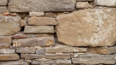 old stone wall background in various colors. The wall of the old historical stone house built with stones one by one