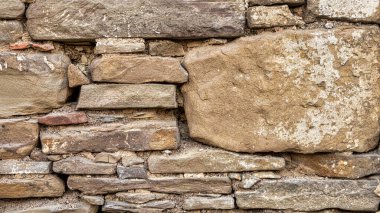 old stone wall background in various colors. The wall of the old historical stone house built with stones one by one