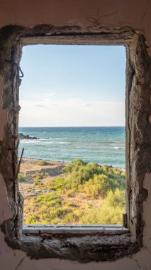 Eski pencere. Güneşli bir yaz gününde terk edilmiş bir evin penceresinden deniz manzarası.