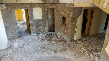Terk edilmiş ve yıkılmış eski bir otel binasının lobisi ve inşaat enkazı etrafa saçılmış.