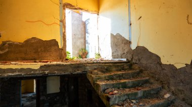 Terk edilmiş ve yıkılmış eski bir otel binasının çatısına çıkan merdivenler ve etrafa saçılmış inşaat enkazı.