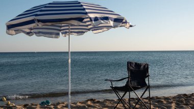 Deniz şemsiyesi ve plajda bir piknik sandalyesi. Yaz havası. Kopyalanacak alan