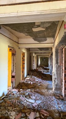 Terk edilmiş ve yıkılmış eski bir otel binasının koridoru ve etrafa saçılmış inşaat enkazı.