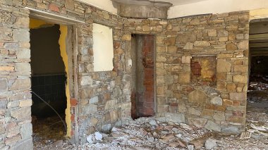 Terk edilmiş ve yıkılmış eski bir otel binasının lobisi ve inşaat enkazı etrafa saçılmış.