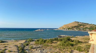 Rüzgarlı bir günde Kalekoy limanı, arka plandaki yüksek dağda demirli tekneler ve Kalekoy kalesi. Gökçeada, Çanakkale, Türk