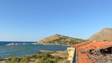 Rüzgarlı bir günde Kalekoy limanı, arka plandaki yüksek dağda demirli tekneler ve Kalekoy kalesi. Gökçeada, Çanakkale, Türkiye