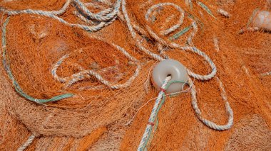 Rıhtımda birbirine dolanmış turuncu balık ağları ve şamandıralar.