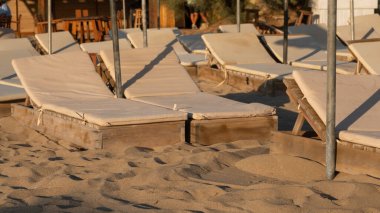 Gün batımında Gkeada Aydincik (Kefalos) plajında boş güneş pansiyonları ve şemsiyeler. anakkale Türkiye