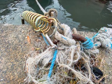 Limandaki kordona modern bir demir kanca askısıyla bağlanmış halat. Balıkçı ekipmanı