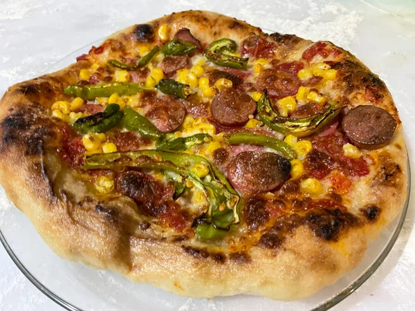 Tradiční Italská Pizza Kukuřicí Paprikou Klobásou Mramorovém Pultu Roztroušenou Moukou Stock Obrázky