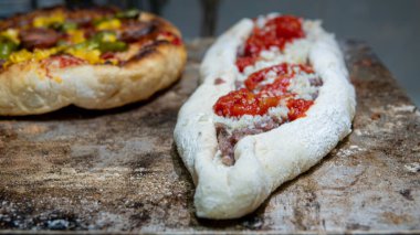  Geleneksel ev yapımı İtalyan pizzası sıcak demir fırında ve hamurda domates soslu Türk pidesi pişirmeye hazır. Görünümü kapat, seçici odak