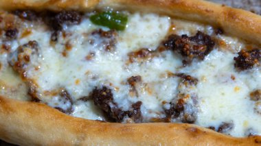 Kıymalı Türk pidesi, yeşil biber ve tabakta mozarella peyniri. Türkçe adı Kiymali Pide. Geleneksel Türk mutfağı. Etli Türk pizzası.