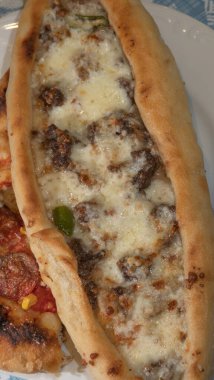 Kıymalı Türk pidesi, yeşil biber ve tabakta mozarella peyniri. Türkçe adı Kiymali Pide. Geleneksel Türk mutfağı. Etli Türk pizzası.