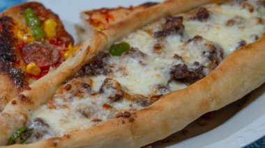 Kıymalı Türk pidesi, yeşil biber ve tabakta mozarella peyniri. Türkçe adı Kiymali Pide. Geleneksel Türk mutfağı. Etli Türk pizzası.