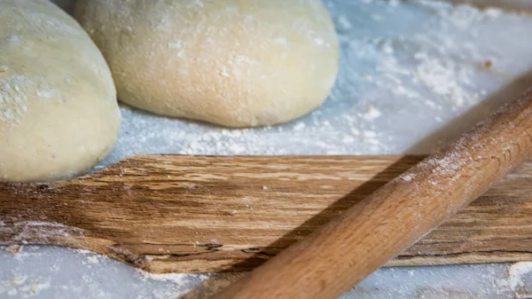 Preparation of raw dough balls with a rolling pins  for cooking pastries on a on the marble counter with flour scattered around.  Traditional Turkish cuisine. close up, selective focus