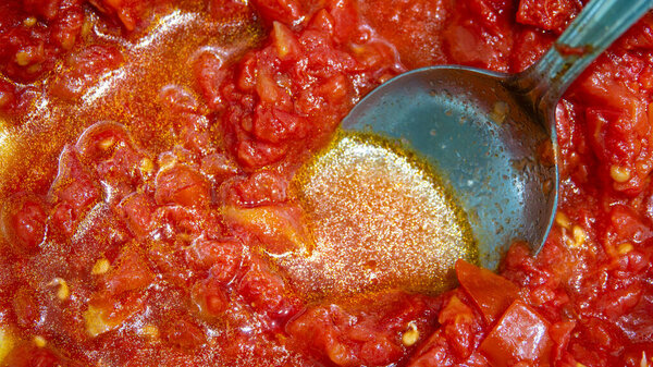 Tomato sauce is fried in a pan with a spoon close-up. Preparation of Italian tomato sauce.