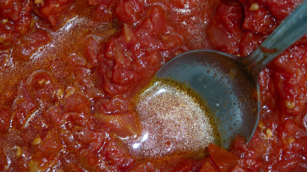Tomato sauce in a pan with a spoon close-up. Preparation of Italian tomato sauce.