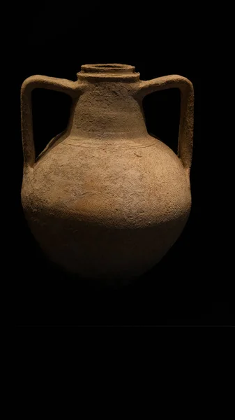 Ancient clay amphora on a black background, close-up.
