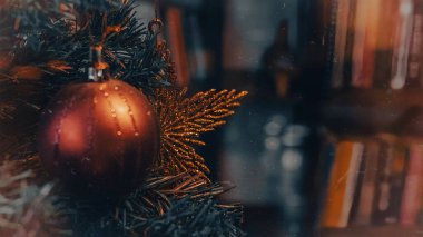 Altın renkli toplarla süslenmiş Noel ağacı altın rengi süslemeli yıldız ve arkaplandaki bulanık kitaplığın önünde elma