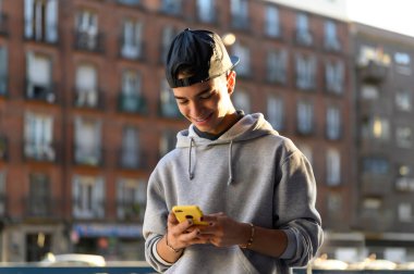 Gülümseyen adam caddedeki telefona bakıyor. 