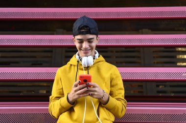 Mutlu adam kulaklık ile müzik dinlemek için bir akıllı telefon kullanma