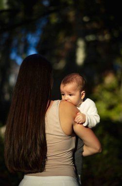 Sırtüstü yatmış bir kadın sokakta oğluna sarılıyor.