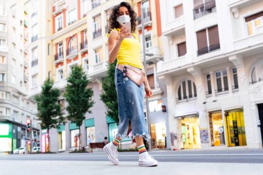 Sokakta yürüyen ve cep telefonuna bakan bir kadın.