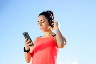 Koşucu kadın akıllı telefonda müzik çalıştırıyor.