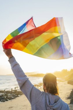 Ayakta duran adam gökkuşağı bayrağını gökyüzüne kaldırdı.