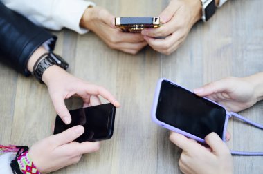 Bir grup Avrupalı kız ellerinde akıllı telefon ya da siyah ekranlı cep telefonu tutuyorlar. Yaşam tarzı serbest çalışma ve pazarlama kavramı