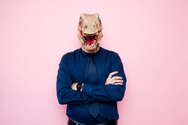Dinozor kafası ve çapraz kolları olan bir adamın portresi. Pembe arka plan.