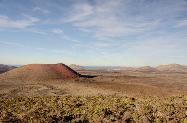 Lanzarote 'deki Roja Dağı' ndan nefes kesici bir manzara, berrak mavi gökyüzü altında volkanik manzaraların engebeli güzelliğini gözler önüne seriyor. Görüntü, kırmızı ve kahverengi renklerin katıksız kontrastını yakalıyor ve macera ve doğal harikalar hissi uyandırıyor. Bunun için ideal